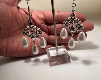 May include: Silver dangle earrings with a filigree design and three white pearl drops.