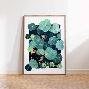 May include: A framed art print featuring a pond scene with koi fish and lily pads. The artwork depicts orange and white koi fish swimming among large, green lily pads. The background is a dark blue, creating a contrast with the bright fish and pads.
