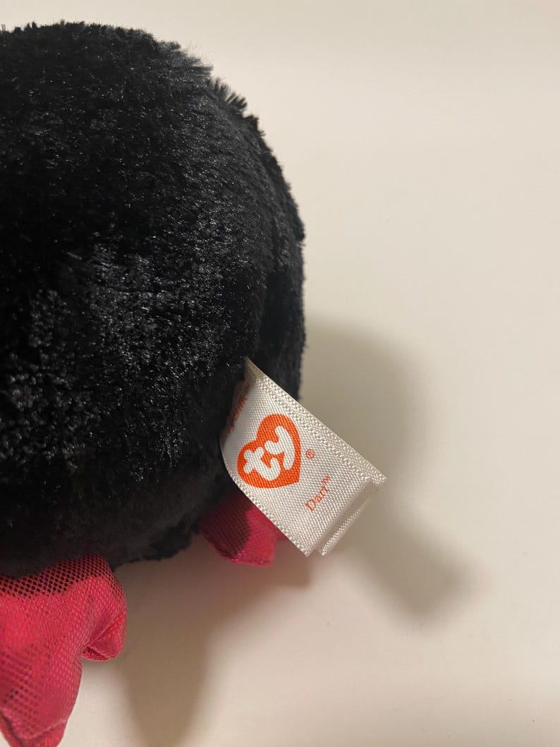 May include: Black plush toy with a red bow and a Ty tag that says "Diaper".