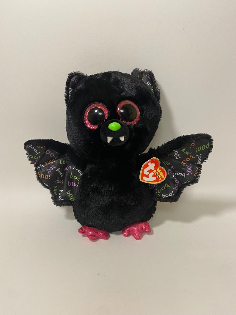 May include: Black plush bat with pink feet and wings. The bat has large, glittery eyes and a green nose. The wings are printed with the words "boo!" and "boo". The bat has a Ty tag attached to its right wing.
