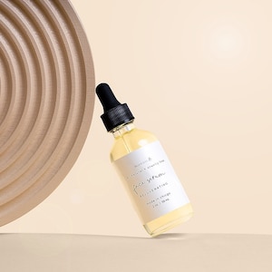 May include: A clear glass bottle with a dropper top containing a face serum. The bottle is labeled "all natural - cruelty free" and "face serum rejuvenating" with the text "made in chicago" and "2 oz. | 50 ml".