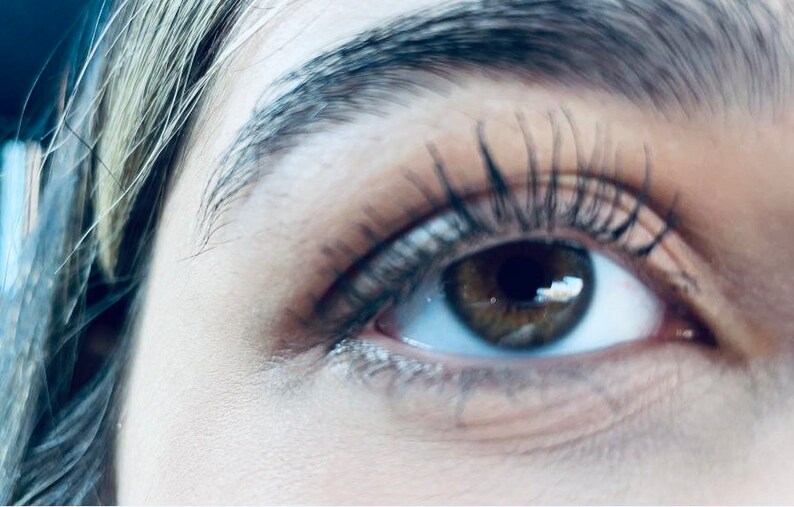 Peut inclure: Gros plan sur l'&oelig;il d'une personne avec de longs cils et un iris brun. L'&oelig;il regarde vers le haut et vers la droite.