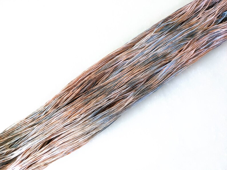 May include: A skein of yarn with a gradient of colors, starting with a light brown and transitioning to a light blue.