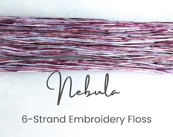 May include: A skein of six-strand embroidery floss in a purple and white colorway called "Nebula".