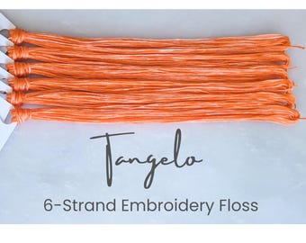 Op de afbeelding: Zes strengen gemêleerd oranje en wit borduurgaren horizontaal gerangschikt. De tekst Tangelo en 6-Strand Embroidery Floss staat onder het garen gedrukt. Het garen is aan de linkerkant bevestigd aan een witte papieren kaart.