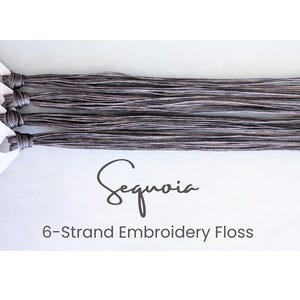 May include: Bundles of Sequoia 6-strand embroidery floss in shades of gray and white. The floss is tied at one end with a white paper tag. The text "Sequoia" is written in cursive, with "6-Strand Embroidery Floss" below it.
