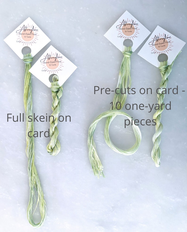 May include: Three skeins of green hand-dyed embroidery floss. One skein is full, and two are pre-cut into 10 one-yard pieces. The floss is labeled "Afterglow Hand-Dyed Floss 10 Yards".