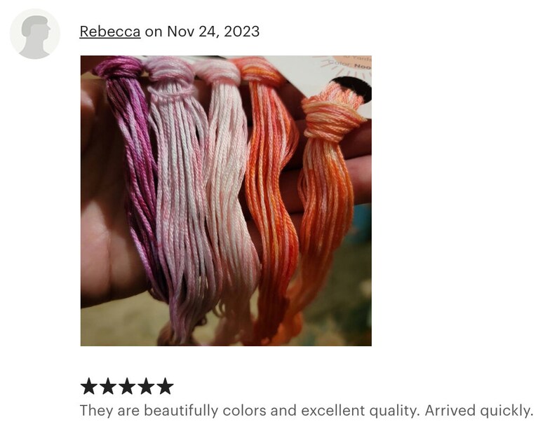 May include: Four skeins of embroidery floss in shades of pink, orange, and red. The floss is arranged in a hand, with the ends of the skeins tied together.