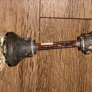 Può includere: Un set di maniglie per porta vintage composto da due pomelli in vetro trasparente scanalato fissati su basi in metallo scuro e usurato. I due pomelli sono collegati da un perno centrale in metallo arrugginito che corre orizzontalmente.