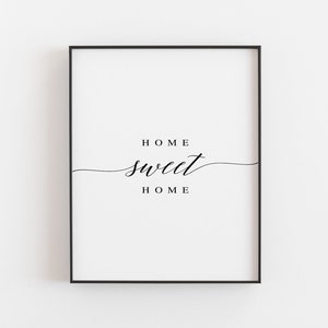 Può includere: Stampa incorniciata in bianco e nero con il testo "HOME sweet HOME" in un carattere corsivo.
