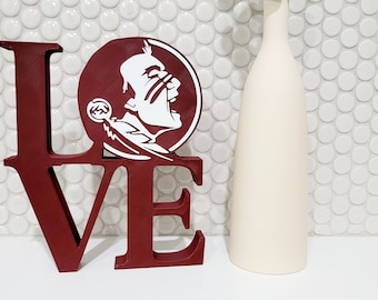 May include: A red wooden "LOVE" sign with a white Seminole State University logo on the "O".