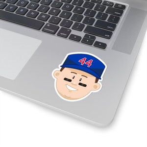 May include: Cartoon illustration of a baseball player wearing a blue cap with the number 44 on it. The player has a mustache and is smiling.