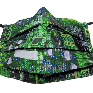 Peut inclure: Un masque facial vert et noir avec un motif de circuit imprimé. Le masque est plissé et possède des boucles d'oreille élastiques.