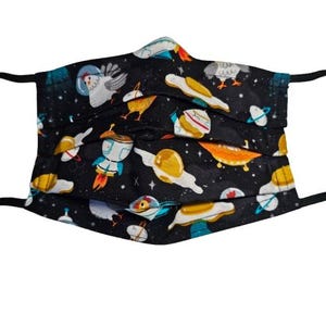 May include: A black face mask with a colorful pattern of chickens, spaceships, planets, and eggs. The pattern is on a black background.