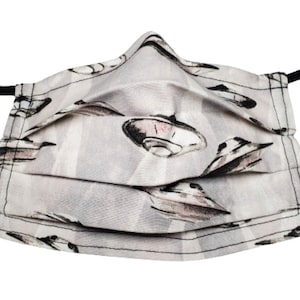 May include: A gray face mask with a white background and a repeating pattern of black and pink flying saucers.