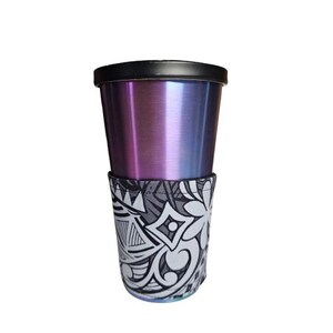 Puede incluir: Un vaso de acero inoxidable con tapa negra y funda. El vaso tiene un acabado que cambia de color, pasando del morado al azul. La funda presenta un patrón tribal en blanco y negro, añadiendo un elemento decorativo.