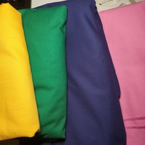 May include: Four fabric swatches in different colors: yellow, green, blue, and pink. The swatches are folded and arranged in a row.