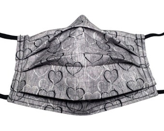 Mascarilla reutilizable ajustable con diseño de corazones grises, con alambre para sujetar la nariz y compartimento para filtro.