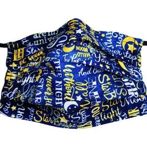 May include: A blue and yellow face mask with a repeating pattern of stars, moons, and the words "Let the Stars Shine", "The Night", "Without End", "Star Bright", and "Never Stop".