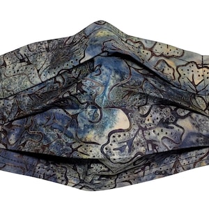 Può includere: Una maschera facciale blu e marrone con motivo e lacci elastici neri per le orecchie. La maschera è realizzata in tessuto e ha un design plissettato.