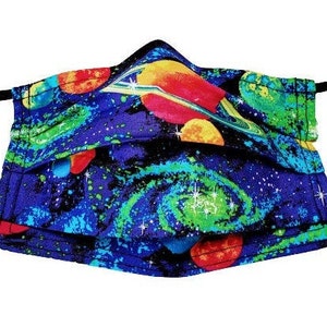 May include: A blue face mask with a colorful galaxy print featuring planets, stars, and swirls. The mask has black elastic ear loops.