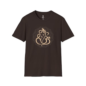 May include: A dark brown t-shirt featuring a beige illustration of the Hindu deity Ganesha within a circular mandala design. The short-sleeved shirt is made of a soft material and is suitable for casual wear.