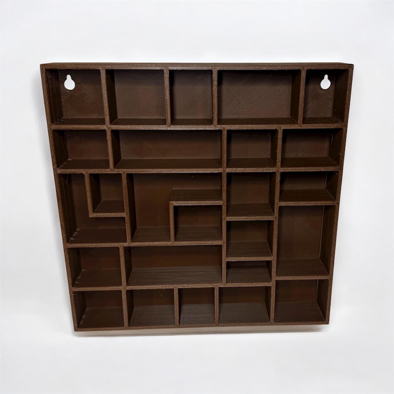 May include: A brown wooden wall-mounted display shelf with multiple compartments of varying sizes. The shelf has a geometric design and includes two keyhole slots for hanging. The shelf is designed to hold small items.
