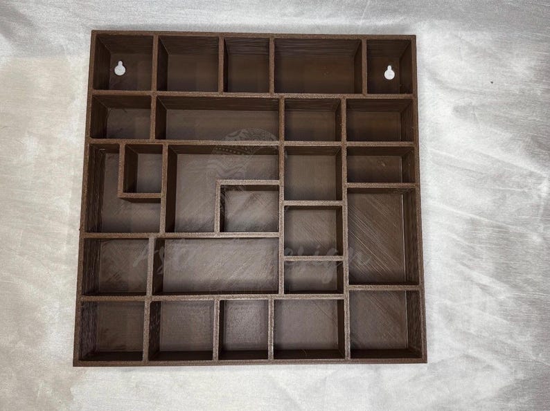 May include: A brown wooden wall-mounted display shelf with multiple compartments of varying sizes. The shelf has a square shape and includes two keyhole slots for hanging. The design is ideal for displaying small collectibles or decorative items.