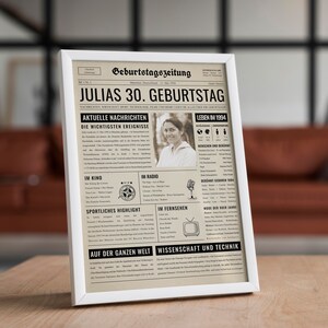 May include: A framed print designed to look like a vintage newspaper, with the headline "JULIAS 30. GEBURTSTAG." The print features a photo of a woman and various sections with text, including "Aktuelle Nachrichten" and "Leben im 1994."