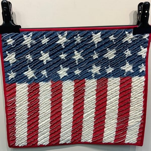 May include: A handmade American flag quilt with red, white and blue fabric. The stars are white on a blue background, and the stripes are red and white.
