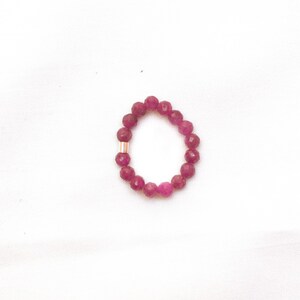 K&ouml;nnte beinhalten: Ein rosa Perlenarmband mit einem goldenen Akzent. Das Armband besteht aus kleinen, runden Perlen und hat einen Umfang von etwa 18 cm.