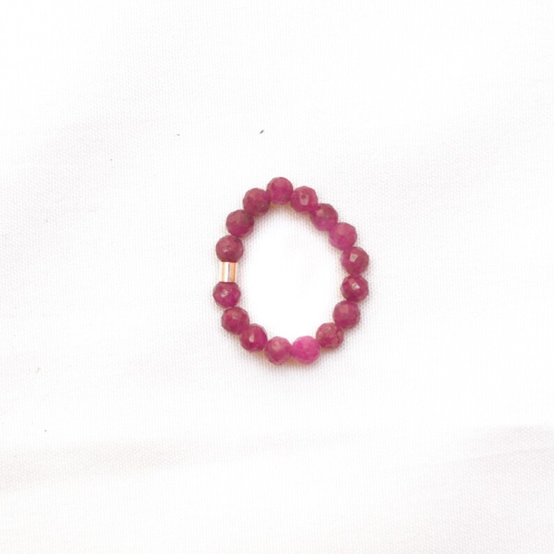 K&ouml;nnte beinhalten: Ein rosa Perlenarmband mit einem goldenen Akzent. Das Armband besteht aus kleinen, runden Perlen und hat einen Umfang von etwa 18 cm.