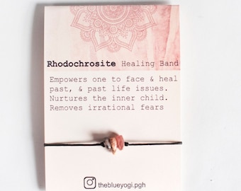 May include: A pink and white mandala design on a card with the text "Rhodochrosite Healing Band" and a description of the stone's healing properties. A black string bracelet with pink and white stones is shown on the card. The Instagram handle "theblueyogi.pgh" is at the bottom of the card.