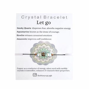 May include: A crystal bracelet with the text "Crystal Bracelet Let go". The bracelet features smoky quartz, aquamarine, howlite, and amazonite beads. The card also includes the text "theblueyogi.pgh".