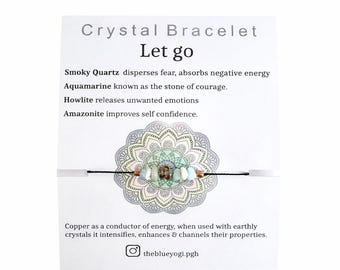 May include: A crystal bracelet with the text "Crystal Bracelet Let go". The bracelet features smoky quartz, aquamarine, howlite, and amazonite beads. The card also includes the text "theblueyogi.pgh".