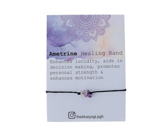 Könnte beinhalten: Ametrin-Heilsband mit violetten und klaren Kristallen auf einer schwarzen Schnur. Die Karte lautet "Ametrine Healing Band Enhances lucidity, aids in decision making, promotes personal strength & enhances motivation" und "theblueyogi.pgh".