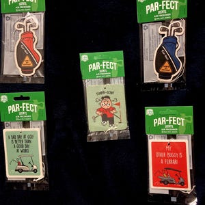 May include: Five Par-Fect Scents air fresheners in individual green packaging. Two are shaped like golf bags with How's My Driving text. One shows a golfer with Temper-Scent text, one a golf cart with A Bad Day at Golf text, and one with My Other Buggy is a Ferrari.