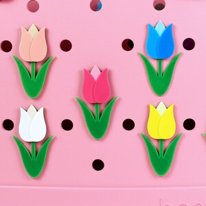 May include: Eight colorful tulip-shaped charms in pink, red, yellow, white, blue, and purple. The charms are arranged on a pink background with black polka dots.