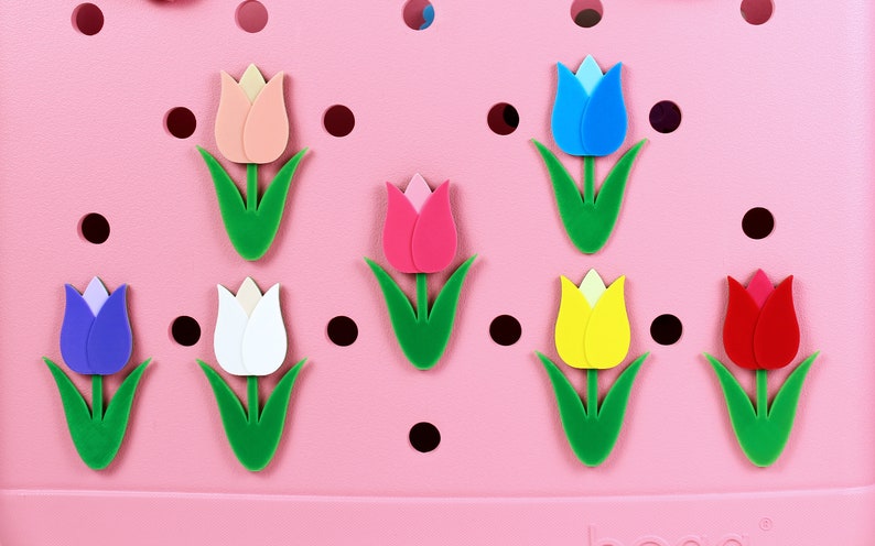 May include: Eight colorful tulip-shaped charms in pink, red, yellow, white, blue, and purple. The charms are arranged on a pink background with black polka dots.