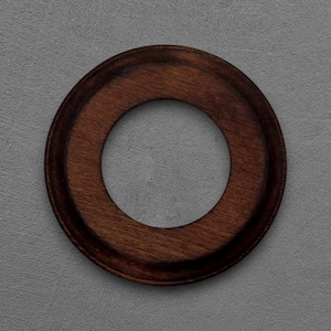 Pode incluir: Um objeto circular de madeira com acabamento castanho escuro. O objeto tem uma borda externa elevada e um orifício central. O grão da madeira é visível, adicionando textura ao design. O objeto está sobre um fundo cinza.