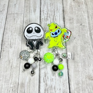 May include: Two Halloween themed retractable badge holders with charms. One features a black and white Jack Skellington character and the other features a green and blue Stitch character dressed as the Grinch.