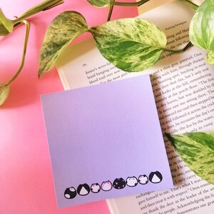 notepad lies on a book in front of pink background, plant trailing around