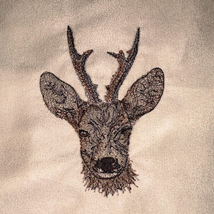 May include: Embroidered deer head with detailed antlers and facial features. The embroidery is in shades of brown and gold against a light beige background. The design is centered, showcasing the deer's face.