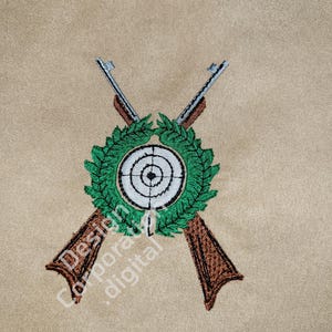 Op de afbeelding: Een geborduurd patch met twee gekruiste geweren en een doelwit in het midden, omringd door een krans in bruin en groen.