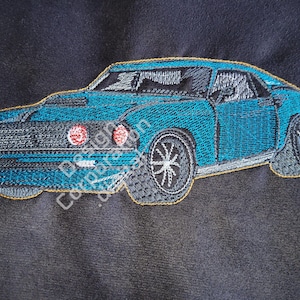 May include: Embroidered image of a blue classic car with a black grill and black wheels. The car is on a dark blue background.