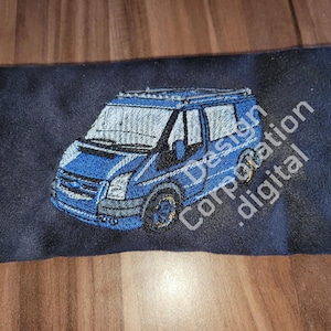 Può includere: Un cuscino in tessuto blu scuro con un furgone blu ricamato, tetto e finestre bianche. Il cuscino è anche ricamato con il testo "Design Corporation .digital".