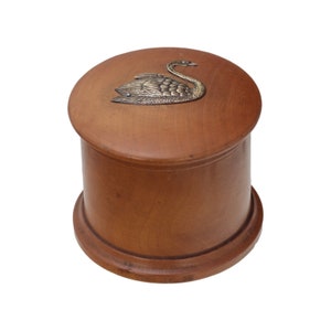 Könnte beinhalten: Eine Holzkiste mit einem Schwanenmotiv auf dem Deckel. Die Kiste ist braun und hat eine runde Form.