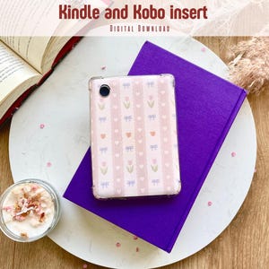 Op de afbeelding: Een roze en witte telefoonhoes met een bloemenpatroon. De hoes ligt op een paars boek. De tekst "Kindle and Kobo insert" staat bovenaan de afbeelding.