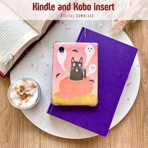 Op de afbeelding: Een roze Kindle- en Kobo-hoesje met een Halloween-ontwerp. Het toont een zwarte kat in een pompoen, omringd door geesten en vleermuizen. De tekst "Kindle and Kobo insert" en "DIGITAL DOWNLOAD" staat bovenaan. De hoes ligt op een paars boek.