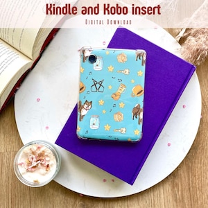 Op de afbeelding: Een blauwe en witte Kindle of Kobo e-reader insert met een ontwerp van muzieknoten, sterren, brillen en een laars. De insert ligt op een paars boek en een wit bord.